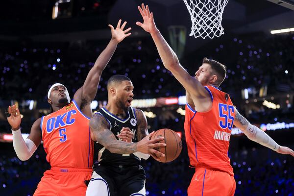 Milwaukee Bucks guard Damian Lillard (0) passes between Oklahoma City Thunder guard Luguentz Dort (5) and center Isaiah Hartenstein (55) during the second half of the championship game in the NBA Cup basketball tournament Tuesday, Dec. 17, 2024, in Las Vegas. (AP Photo/Ian Maule)