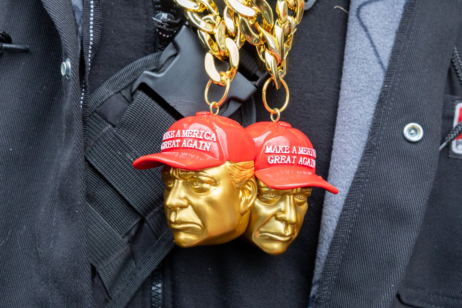 A vendor wears Trump necklaces while selling merchandise to supporters waiting to enter a Trump rally at Capital One Arena in Washington, D.C. on Sunday, January 19, 2025, one day before Donald Trump’s inauguration. (Arvin Temkar / AJC)