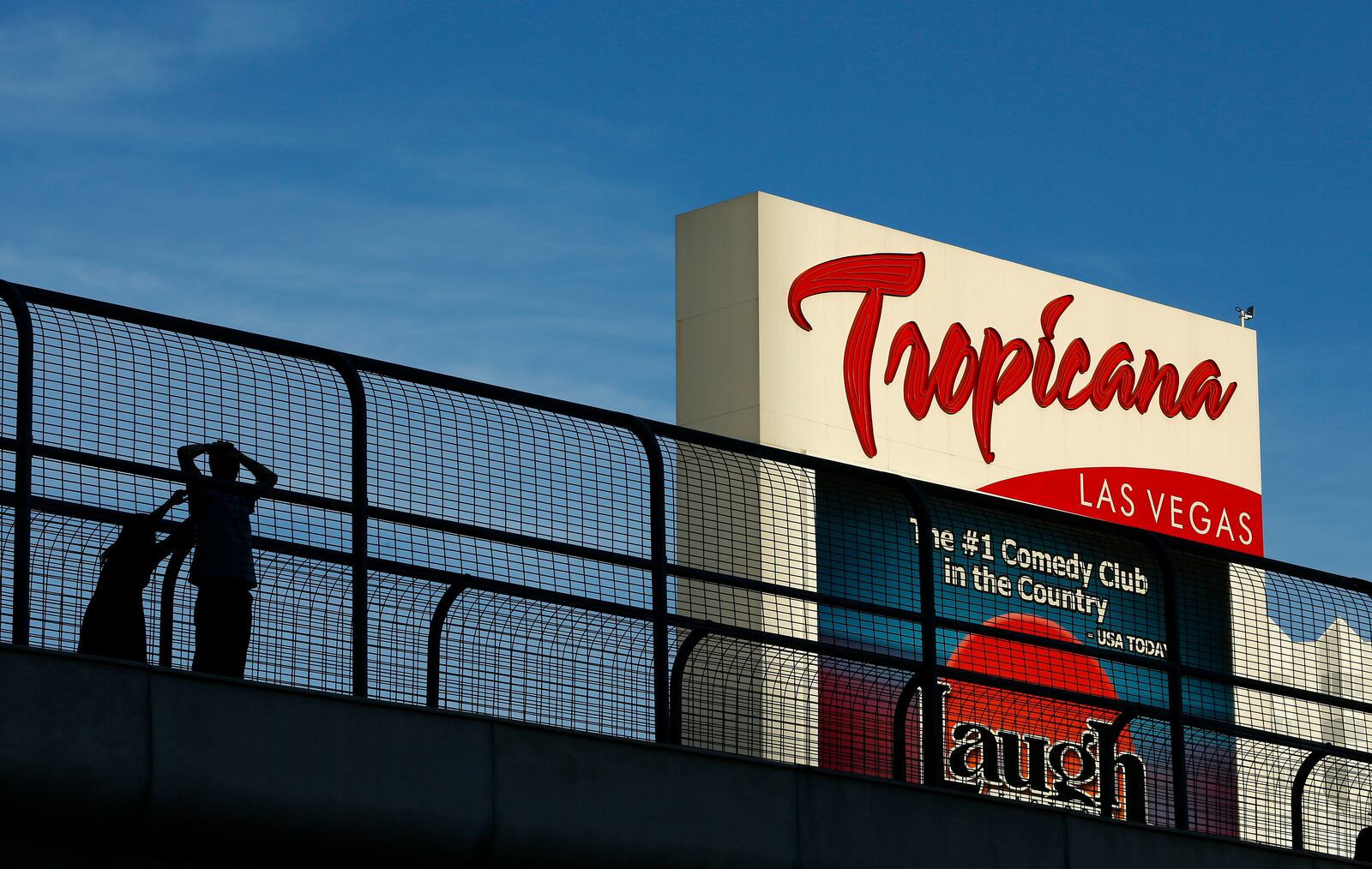 FILE - People stand on a pedestrian bridge by the Tropicana hotel and casino, Aug. 4, 2015, in Las Vegas. (AP Photo/John Locher, File)