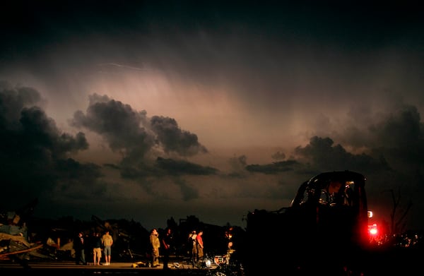 FILE- Emergency workers wait for a medical team after finding a body in a tornado ravaged car in Joplin, Mo., Monday, May 23, 2011. (AP Photo/Charlie Riedel, File)