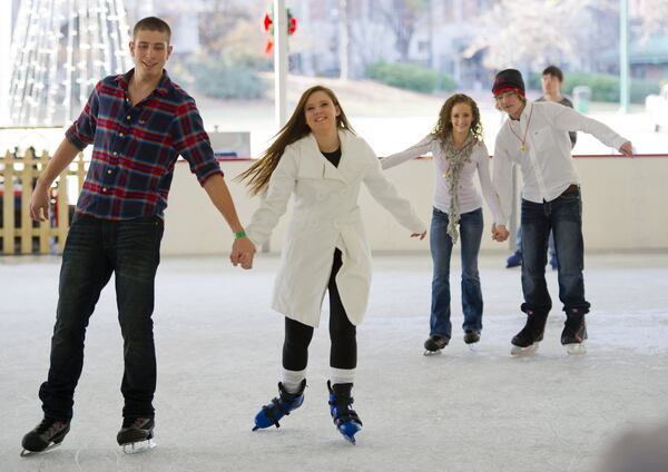 Daniel Stevenson (left) holds hands with Krista Smith while Katelyn Perna holds hands with Tyler Smith as they skate around the rink at Centennial Olympic Park in downtown Atlanta in 2012.