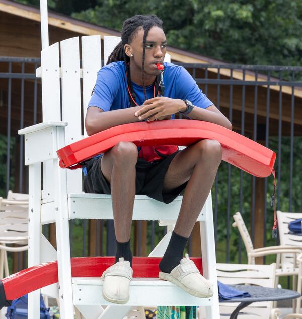 Lifeguard Santories Williams watches swimmers atop his stand at the East Lake Family YMCA pool in Atlanta on June 28, 2024. PHIL SKINNER FOR THE ATLANTA JOURNAL-CONSTITUTION