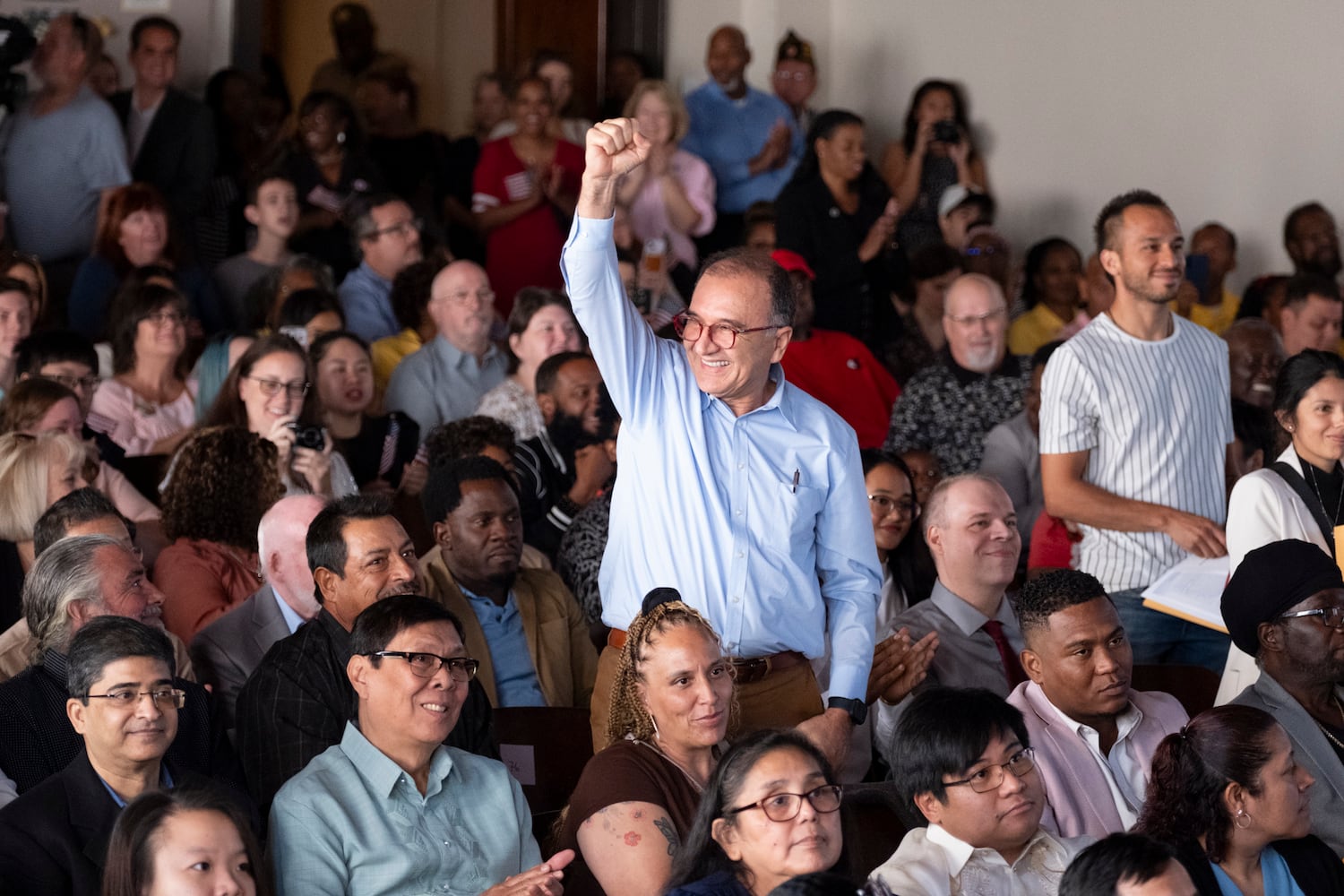 Henry Tovar, who is from Columbia, stands and pumps his fist when his country is named during a Naturalization ceremony at Jimmy Carter National Historic Park in Plains on Tuesday, Oct. 1, 2024, where he became a U.S. citizen. The ceremony was held in honor of President Carter’s 100th birthday.  Ben Gray for the Atlanta Journal-Constitution