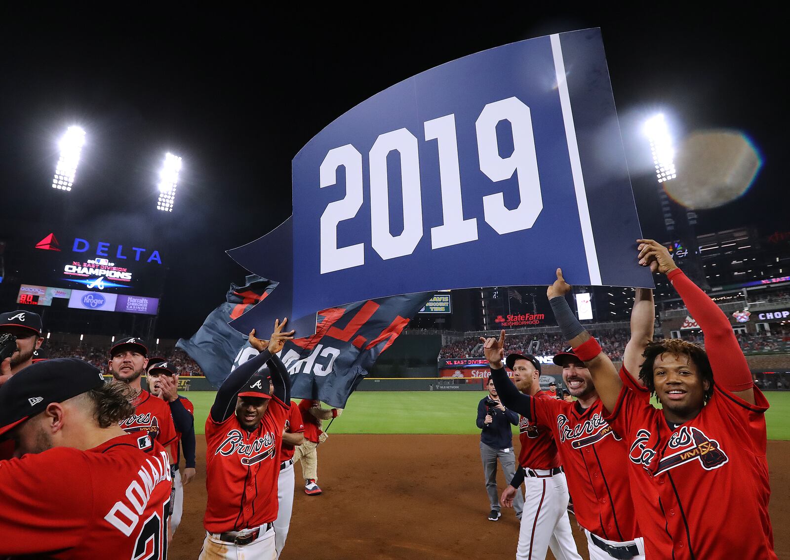 Atlanta Braves Ozzie Albies (left), Ronald Acuna Jr. and teammates raise the banner as they clinch the National League East title with a 6-0 victory over the San Francisco Giants in a MLB baseball game on Friday, Sept. 20, 2019, in Atlanta.  Curtis Compton/ccompton@ajc.com