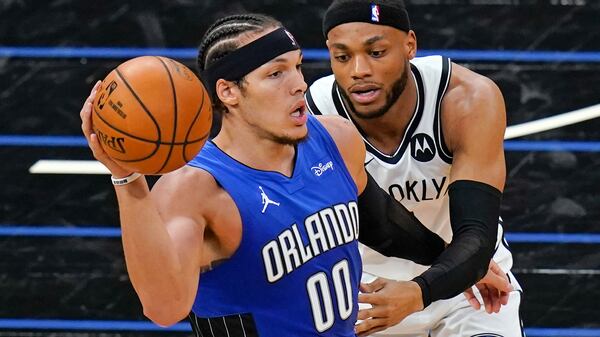 Orlando Magic forward Aaron Gordon (00) passes the ball as Brooklyn Nets forward Bruce Brown, right, guards him during the first half of an NBA basketball game, Friday, March 19, 2021, in Orlando, Fla. (AP Photo/John Raoux)