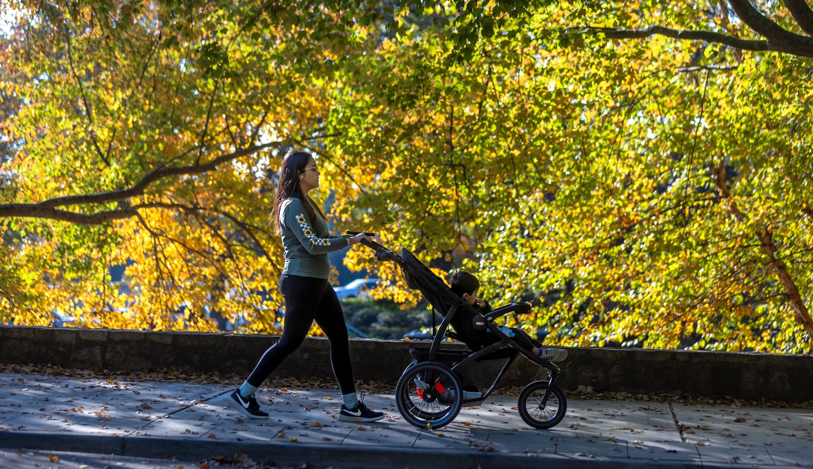 Gabriela Santos strolls past the autumn foliage on Oct. 29 at Chastain Park in Atlanta. John Spink/AJC