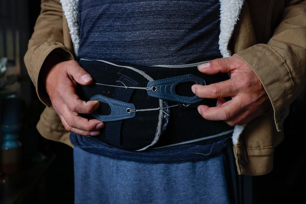 Jovito Caballero shows the back brace belt he wears all day to withstand back pain after an injury forced him to stop working. Caballero is currently involved in a legal dispute with Pilgrim’s Pride, which he worked for, for more than 20 years. 
Miguel Martinez /miguel.martinezjimenez@ajc.com