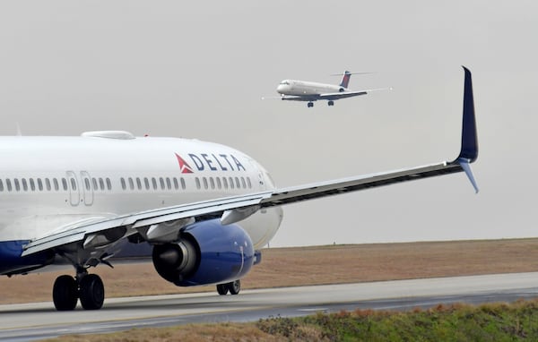 A Delta Air Lines jet prepares to take off as another jet approaches at Hartsfield-Jackson International Airport. HYOSUB SHIN / HSHIN@AJC.COM