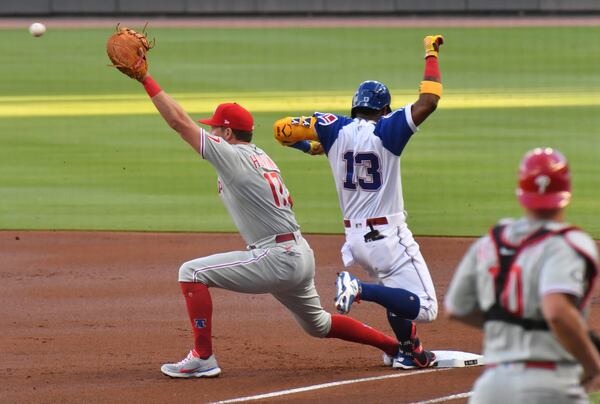 Braves right fielder Ronald Acuna (13) toes first base before the ball reaches Philadelphia Phillies first baseman Rhys Hoskins (17) in the first inning Sunday, April 11, 2021, at Truist Park in Atlanta. (Hyosub Shin / Hyosub.Shin@ajc.com)