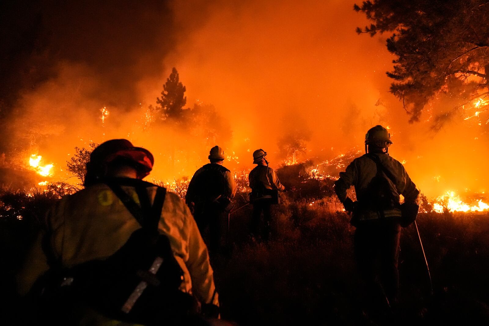 Firefighters watch as the Bridge Fire burns near homes in Wrightwood, Calif., Tuesday, Sept. 10, 2024. (AP Photo/Jae C. Hong)