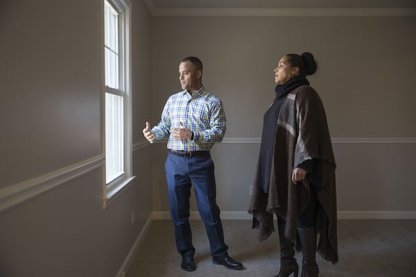 Atlanta Engel & Völkers real estate advisor Erik Dowdy, center, and potential home buyer Katherine Brown peak out a window of the master bedroom of a house listed by Opendoor, an online service that advertises a simplified process to selling, buying or trading a home. ALYSSA POINTER/ALYSSA.POINTER@AJC.COM