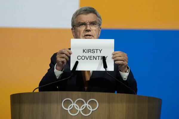 IOC President Thomas Bach holds up the name of Kirsty Coventry as she is announced as the new IOC President at the International Olympic Committee 144th session in Costa Navarino, western Greece, Thursday, March 20, 2025. (AP Photo/Thanassis Stavrakis)