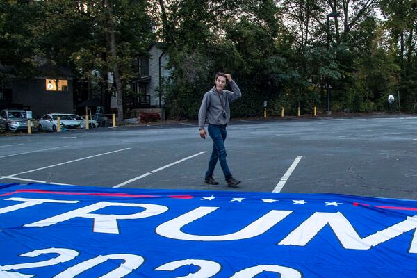 11/05/2020 —  Atlanta, Georgia — Bruno Cua unfurls a large Trump flag during a rally in the parking lot at the Georgia Republican Party headquarters in Buckhead on Thursday, November 5, 2020.  (Alyssa Pointer / Alyssa.Pointer@ajc.com)