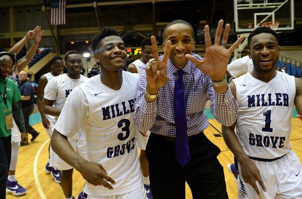 Miller Grove Wolverines head coach Sharman White holds up 7 fingers for their 7th championship win. He's flanked by Alterique Gilbert (3)j. KENT D. JOHNSON/ kdjohnson@ajc.com