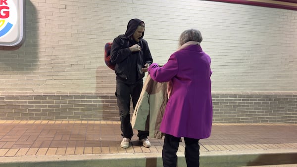 June O'Neal, right, offers a jacket to a man outside a Burger King in downtown Macon, Georgia on Tuesday Jan. 16, 2024. Overnight temperatures plunged into the upper teens.