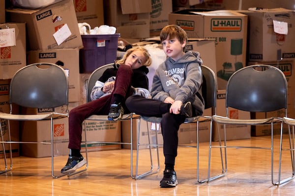 Boxes filled with donations for the people impacted by the wildfires are displayed behind students with the Theatre Palisades' youth theatre program during a master class with American actress and singer Kerry Butler after their theater was destroyed by the Palisades Fire, at the Saint Monica Preparatory's auditorium in Santa Monica, Calif., Sunday, Jan. 26, 2025. (AP Photo/Etienne Laurent)