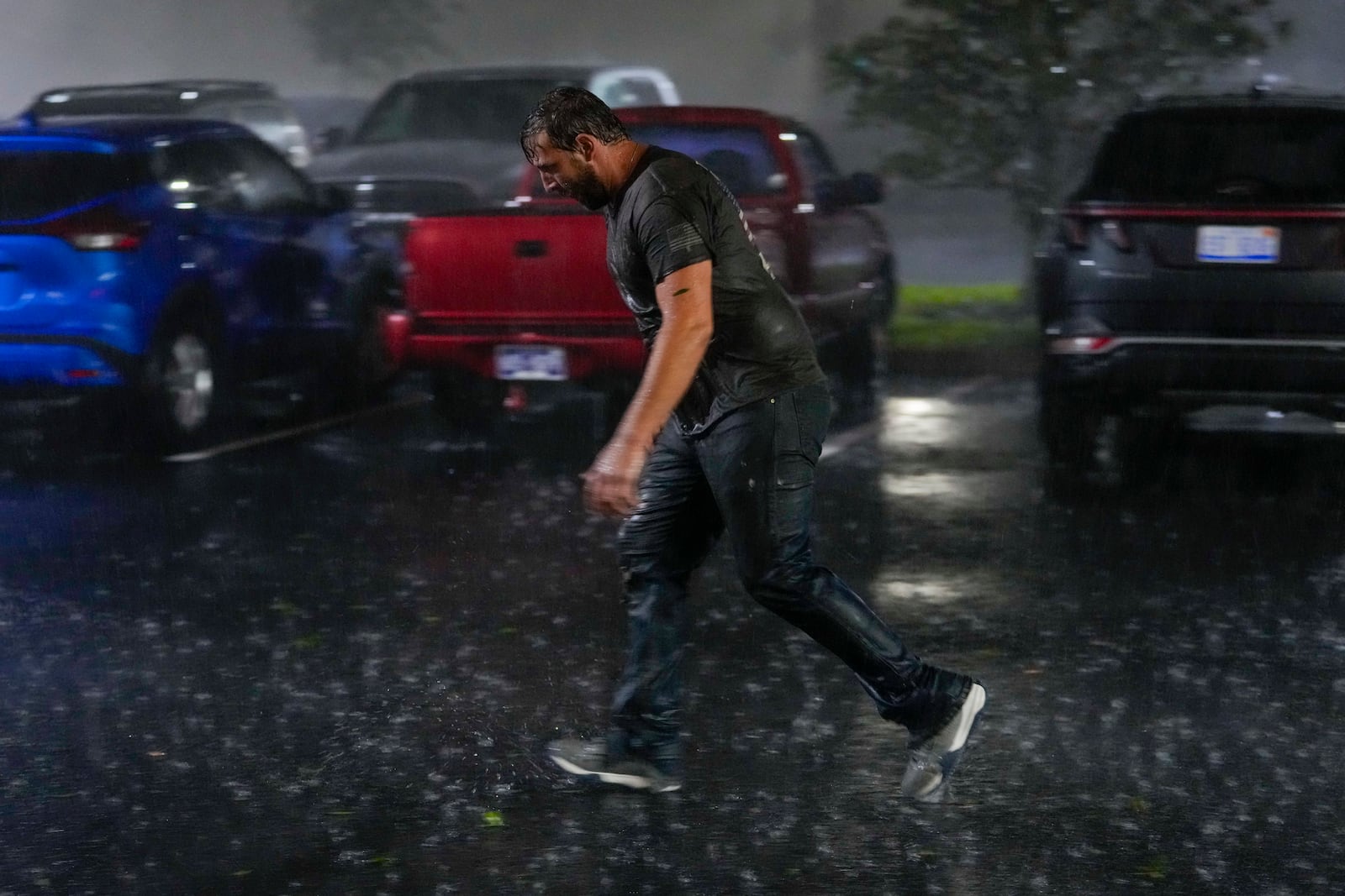 Chris Nation, of Commerce, Ga., skids on puddles in the parking lot of the hotel where he's riding out Hurricane Milton, Wednesday, Oct. 9, 2024, in Tampa, Fla. Nation, who works for a towing company, was deployed to Florida to aid in the aftermath of the storm. (AP Photo/Julio Cortez)