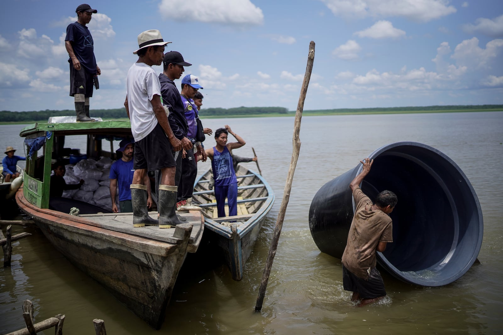 A man from the Tikuna Indigenous community carries a cistern from a nonprofit that can be used to catch and store rainwater for the community amid a drought in Loma Linda, near Leticia, Colombia, Sunday, Oct. 20, 2024. (AP Photo/Ivan Valencia)