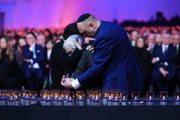 A Holocaust survivor, centre, receives assistance and comfort as she places a candle during the Commemoration Ceremony of the 80th Anniversary of the Liberation of Auschwitz, in Oswiecim, Poland, Monday, Jan. 27, 2025. (Sean Kilpatrick/The Canadian Press via AP)