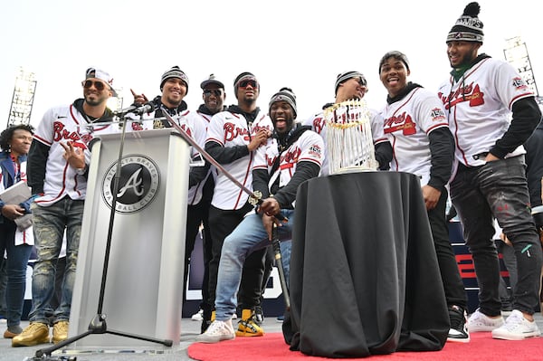 Braves players pose in front of the championship trophy. (Hyosub Shin / Hyosub.Shin@ajc.com)