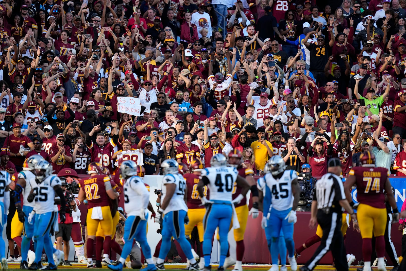 Washington Commanders fans celebrate after a touchdown run by Commanders running back Brian Robinson Jr. during the first half of an NFL football game against the Carolina Panthers, Sunday, Oct. 20, 2024, in Landover, Md. (AP Photo/Stephanie Scarbrough)