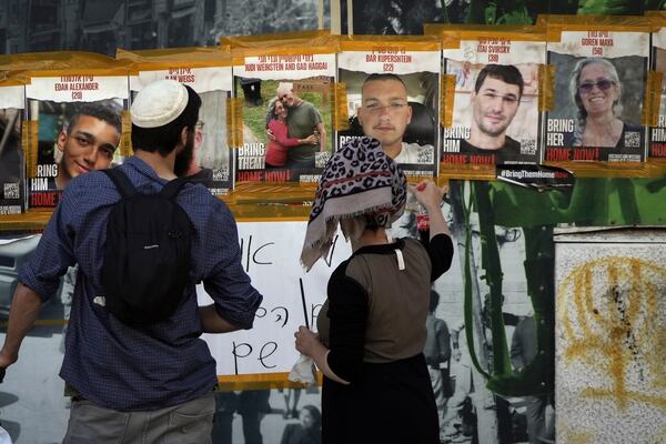 In this picture taken May 25, 2024, people looks at pictures of Hamas hostages, including Itay Svirsky, second from right, in Jerusalem. The Israeli military said Wednesday it had retrieved from Gaza the body of Svirsky who was taken hostage on Oct. 7, 2023, by Hamas and then killed in captivity.(AP Photo/Mahmoud Illean)