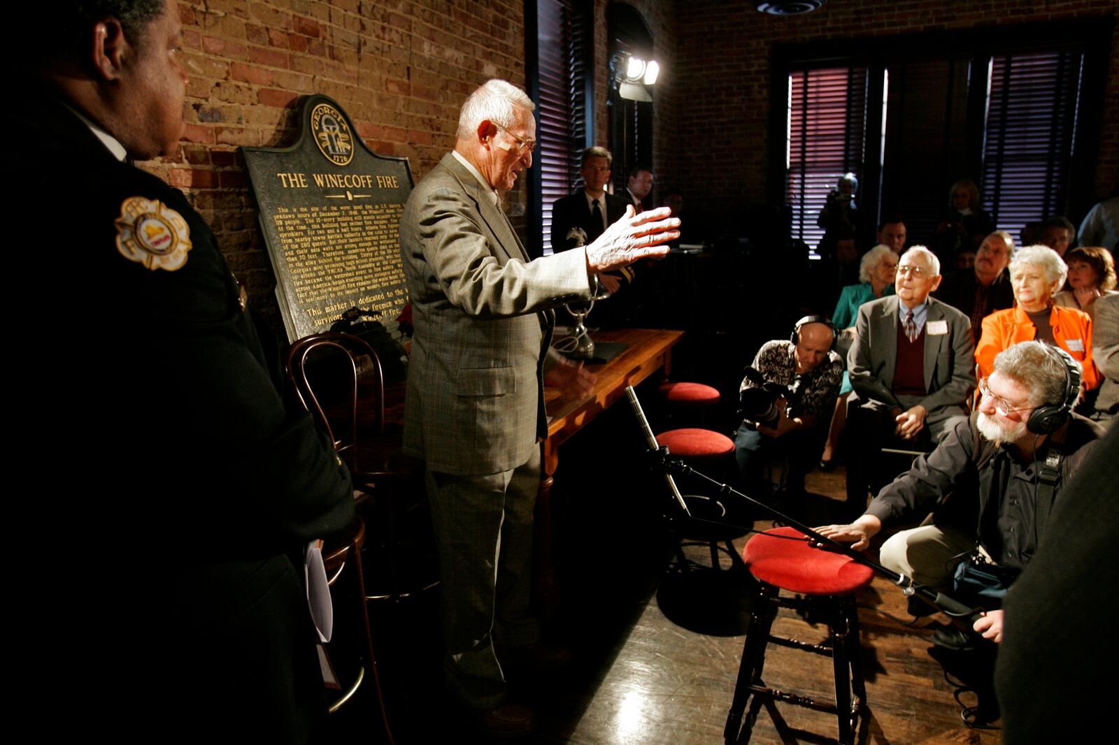 Rick Roberts speaks to people gathered at The Spotted Dog -- which used to house Fire Station 11 -- during a commemoration to mark the 60th anniversary of the Winecoff Hotel fire in downtown Atlanta. Roberts, a firefighter at the time who went on to become battalion chief, is credited with helping to save several of the survivors. The fire, at 119 deaths, the worst hotel fire in U.S. history, caused departments across the country to update their fire safety codes. (Allen Sullivan / Special)