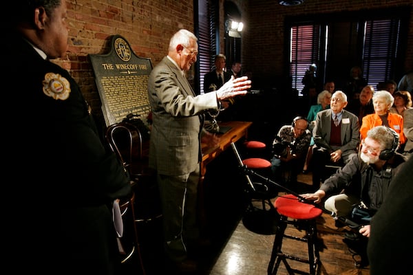 Rick Roberts speaks to people gathered at The Spotted Dog -- which used to house Fire Station 11 -- during a commemoration to mark the 60th anniversary of the Winecoff Hotel fire in downtown Atlanta. Roberts, a firefighter at the time who went on to become battalion chief, is credited with helping to save several of the survivors. The fire, at 119 deaths, the worst hotel fire in U.S. history, caused departments across the country to update their fire safety codes. (Allen Sullivan / Special)