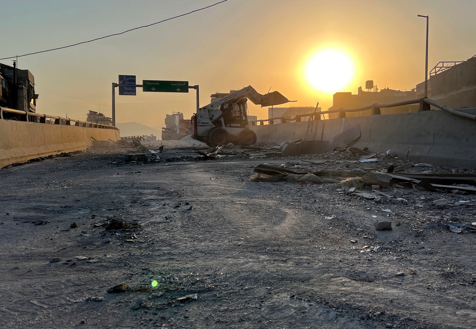 A municipality worker uses a skid steer loader to reopen a bridge closed by the rubble of a destroyed building that was hit by an Israeli airstrike on Dahiyeh, as the sunrise in the southern suburb of Beirut, Lebanon, Friday, Nov. 1, 2024. (AP Photo/Hussein Malla)