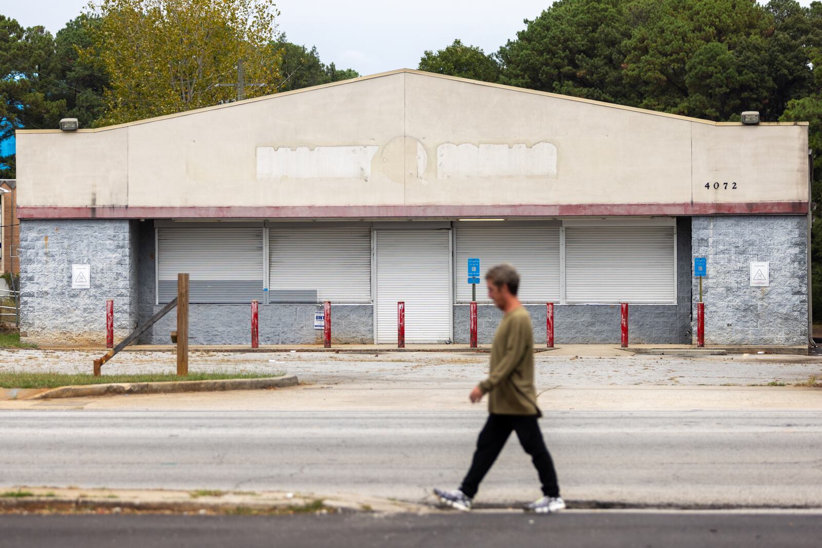 A pedestrian passes a former Family Dollar along Glenwood Road near its intersection with Columbia Drive in southern DeKalb County on Wednesday, Sept. 25, 2024. (Arvin Temkar / AJC)