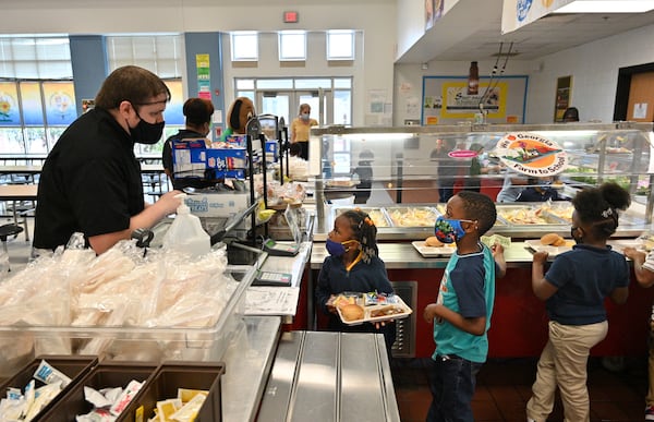 Asher Keeney (left), cafeteria manager, serves kindergarteners at school cafeteria at Cliftondale Elementary School in College Park on Wednesday, Oct. 13. Metro Atlanta school districts are having to be creative to revise and rework menus because of national food supply issues. The COVID-19 pandemic has made it difficult for districts to get some of their usual food items. (Hyosub Shin / Hyosub.Shin@ajc.com)