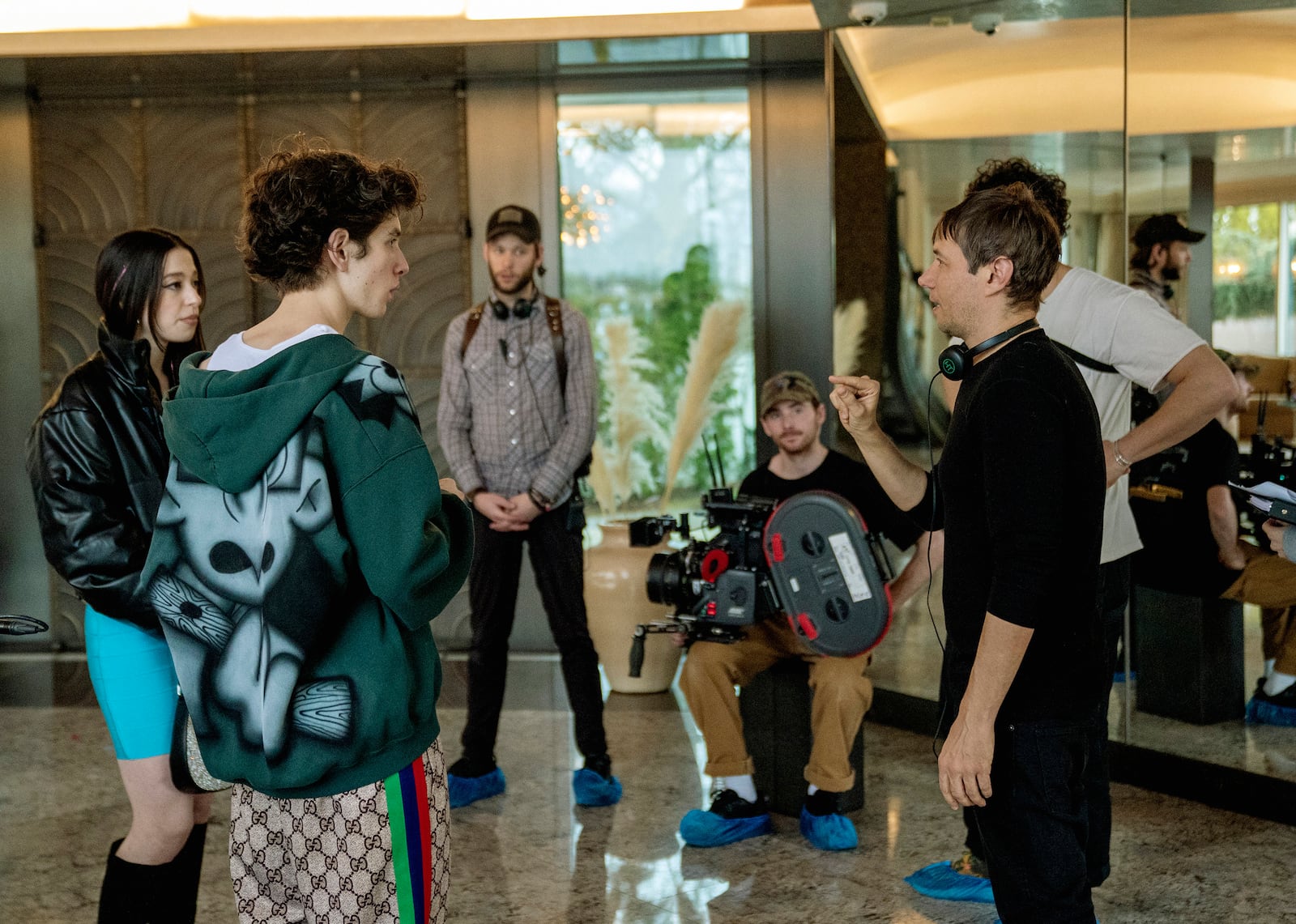 This image released by Neon shows Mikey Madison, left, and Mark Eydelshteyn, second left, with director Sean Baker, right, on the set of "Anora." (Augusta Quirk/Neon via AP)