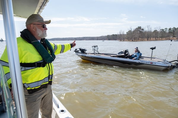 Putnam County sheriff's deputy J.D. Turk, with the Putnam County Sheriff’s Office, directs boats to slow down and avoid an area being searched for the body of Gary Jones in Lake Oconee northeast of Eatonton on Saturday, March 8, 2025.   Ben Gray for the Atlanta Journal-Constitution