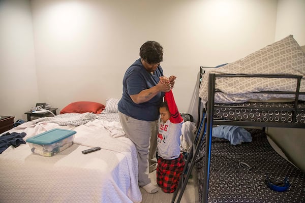 Pearl Lilly attempts to get her grandson, Corbin, out of bed so that he can get ready for school on Wednesday, Feb. 26, 2020. (ALYSSA POINTER/ALYSSA.POINTER@AJC.COM)