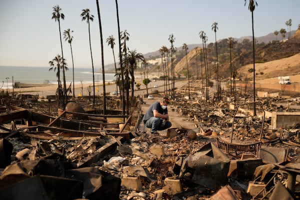 Kevin Marshall sifts through his mother's fire-ravaged property in the the Palisades Fire in the Pacific Palisades neighborhood of Los Angeles, Saturday, Jan. 11, 2025. (AP Photo/John Locher)