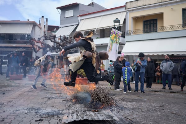 A boy dressed in animal skins and heavy bronze bells, jumps over a burning carnival effigy during carnival celebrations in Distomo, a village in central Greece, on Monday, March 3, 2025. (AP Photo/Petros Giannakouris)