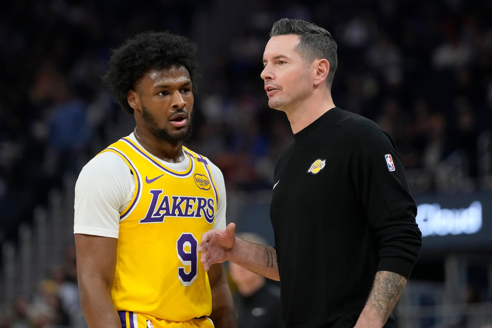 Los Angeles Lakers head coach JJ Redick, right, talks with Los Angeles Lakers guard Bronny James (9) during the first half of an NBA preseason basketball game against the Golden State Warriors in San Francisco, Friday, Oct. 18, 2024. (AP Photo/Jeff Chiu)