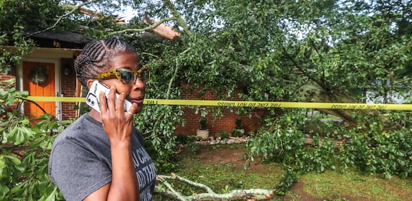 Leisa Stafford talks on the phone outside her Mesa Drive home that was crushed by a tree Thursday morning. Stafford escaped out of a bathroom window.