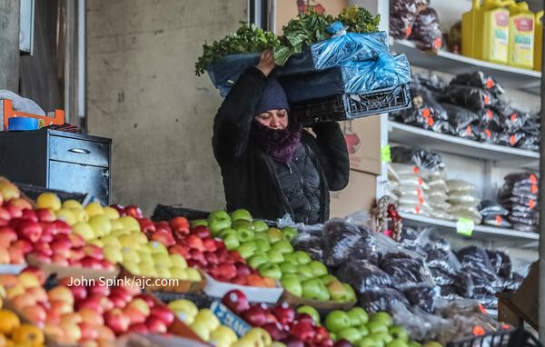 Rosy Aguilar braves the frigid Monday morning air to set up a fruit stand at the Atlanta State Farmers Market in Forest Park.