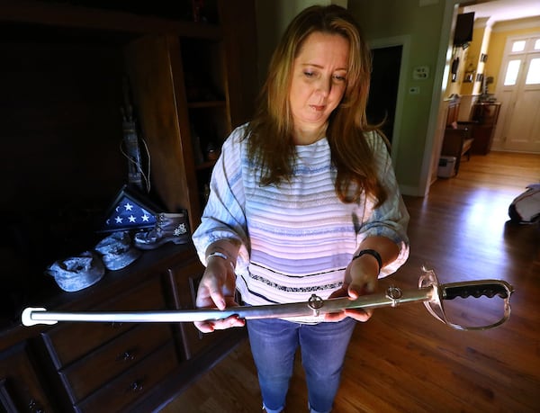 Tammy McCracken holds the sword her husband, David, received when he was promoted to colonel. On the same day he learned of his promotion, doctors performed a biopsy and discovered he had brain cancer. His wife believes his exposure to open-air burn pits in Iraq caused his fatal illness. Curtis Compton/ccompton@ajc.com