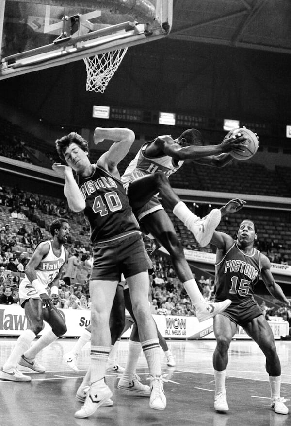 Atlanta Hawks Dominique Wilkings sails out with a rebound Thursday between Detroit Pistons center Bill Laimbeer (40) and guard Vinnie Johnson (15) at Atlanta Omni, February 24, 1983. At left is foreward Dan Roundfield of the hawks in their National Basketball Association game. (AP Photo/Ben Baxter)