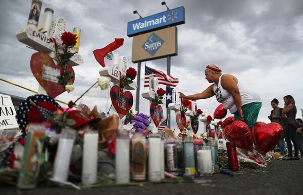 A woman touches a cross at a makeshift memorial for victims outside Walmart, near the scene of a mass shooting which left at least 22 people dead in El Paso, Texas.