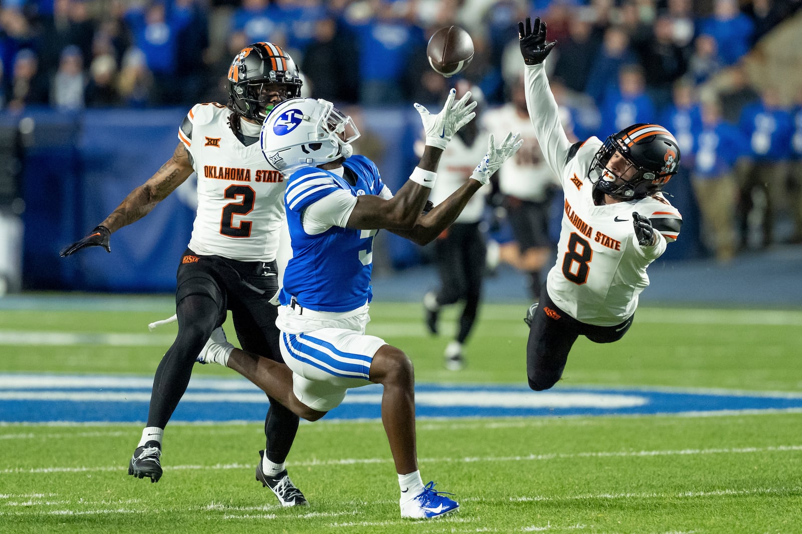 BYU wide receiver Darius Lassiter makes a catch ahead of Oklahoma State cornerback Korie Black (2) and safety Parker Robertson (8) in the first half of an NCAA college football game, Friday, Oct. 18, 2024, in Provo, Utah. (AP Photo/Spenser Heaps)