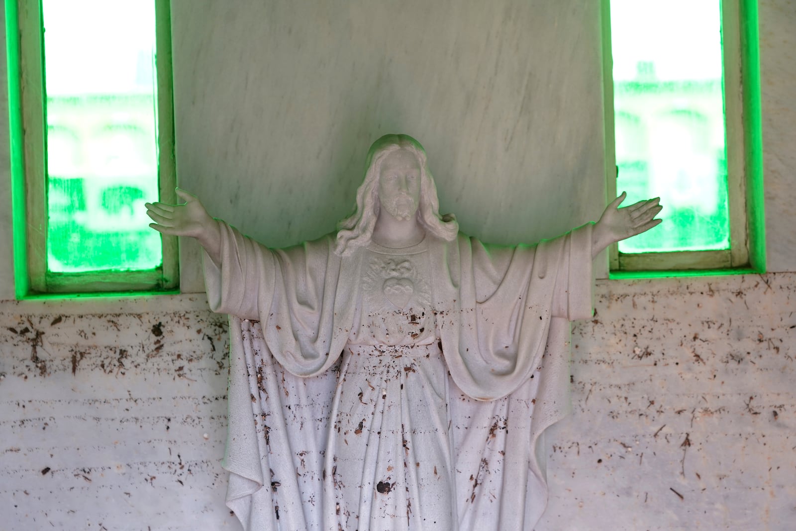 A mud splattered statue of Christ is seen inside a cemetery on the outskirts of Valencia, Spain, Friday, Nov. 1, 2024 after flooding in the region. (AP Photo/Alberto Saiz)