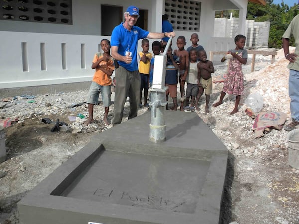 Civil rights attorney Ed Buckley built more than 330 artesian wells and water reservoirs, providing water for nearly 350,000 people in Haiti, since he founded the nonprofit Water Life Hope in 2005. He is pictured here with some of the region’s children at one of the newest wells. (Courtesy)