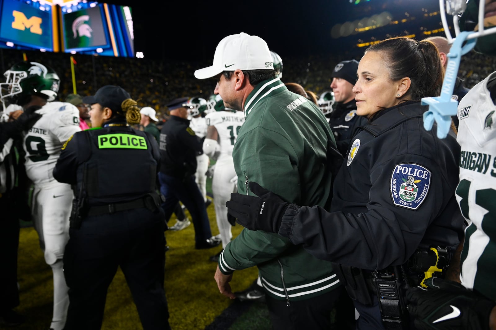 A Michigan State University policewoman holds back head coach Jonathan Smith from getting in the middle of a fight that broke out against Michigan following an NCAA college football game, Saturday, Oct. 26, 2024, in Ann Arbor, Mich. (AP Photo/Jose Juarez)