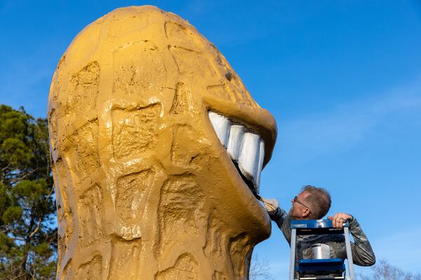 Plains resident Michael Dominick paints the "Smiling Peanut" in Plains on Sunday. (Arvin Temkar / arvin.temkar@ajc.com)