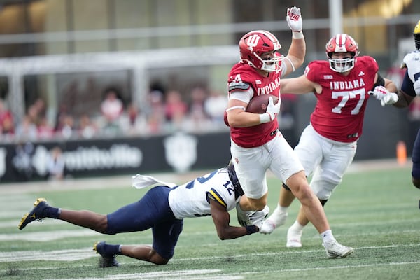 Indiana tight end Zach Horton (44) escapes a tackle by Michigan defensive back Aamir Hall (12) during the first half of an NCAA college football game in Bloomington, Ind., Saturday, Nov. 9, 2024. (AP Photo/AJ Mast)