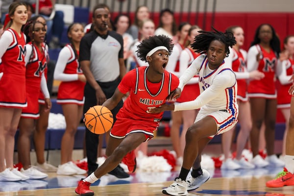 Milton High School guard Josh Dixon (center) dons quite the expression as he drives against Riverwood's Noah Cockrell during the second half of their Class 5A state playoff game Wednesday.