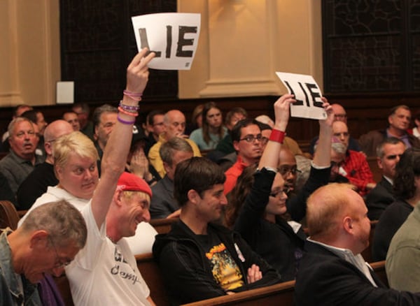 A TOUGH ROOM--Some audience members hold up signs to disagree with an answer by Mayor Kasim Reed and APD Chief George Turner at the Atlanta Police Department LGBT Advisory Board Community Town Hall Meeting to discuss the Atlanta Eagle raid and the city's response to the aftermath at St. Mark United Methodist Church in Atlanta on Tuesday, Nov. 1, 2011.